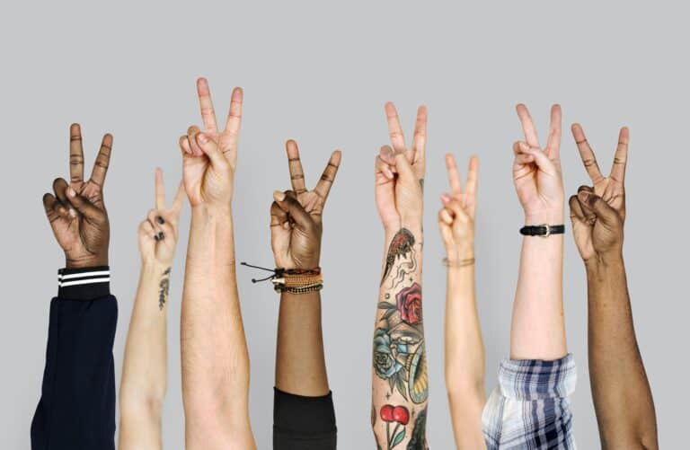 several different races raising hands with peace sign