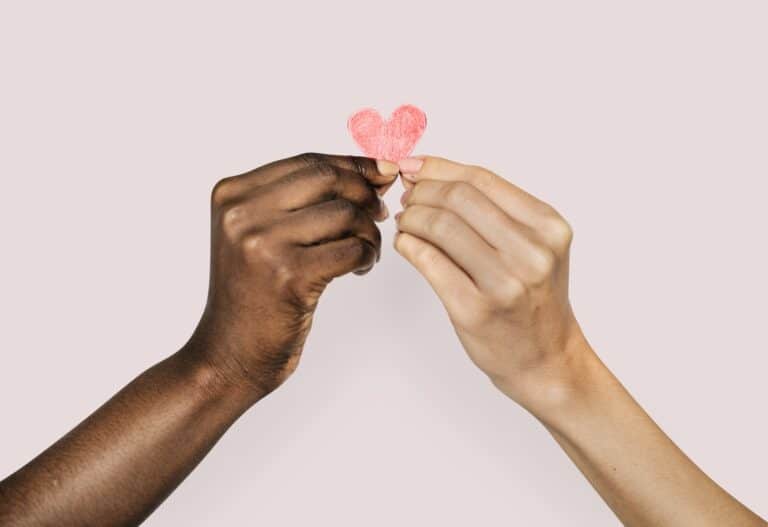 black person & white person fingers holding heart together