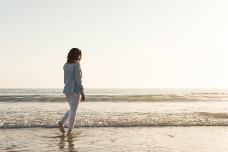 woman walks beach while trying to start over