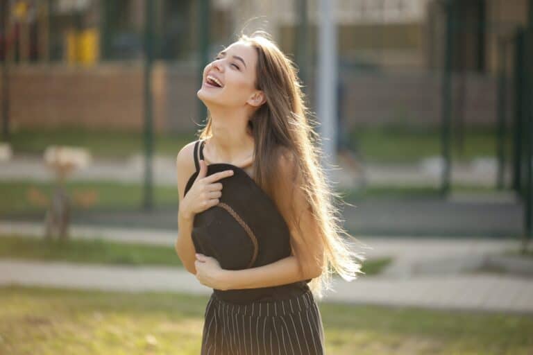 woman holding her hat to her chest as she is laughing because laughter is good for the soul