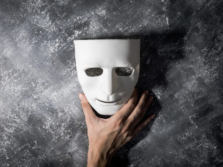 hand holding mask for someone pretending to be someone they're not