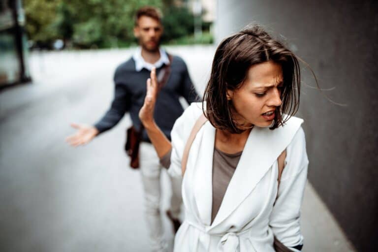 woman walking away from man waving him to go away in a toxic relationship