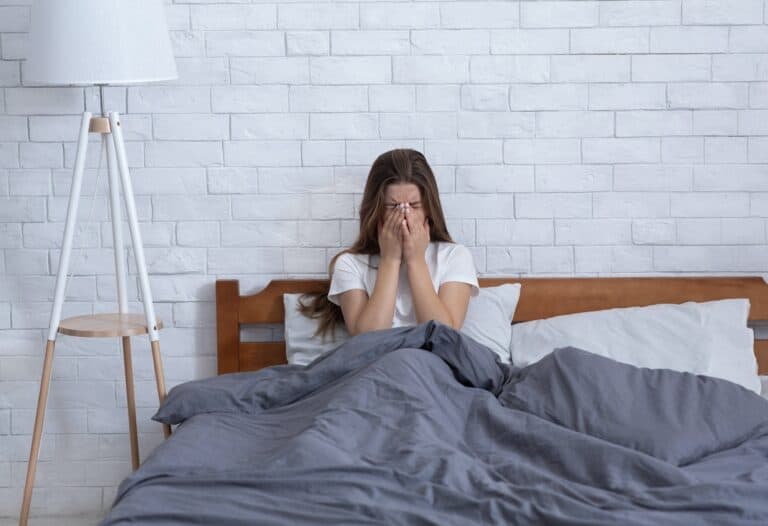 young woman crying alone in her bed at home