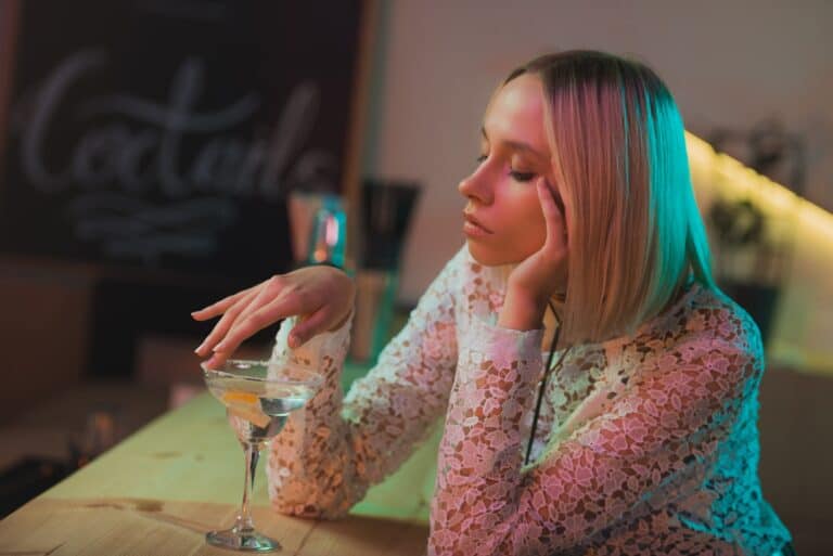 portrait of pensive lonely woman with cocktail sitting in bar
