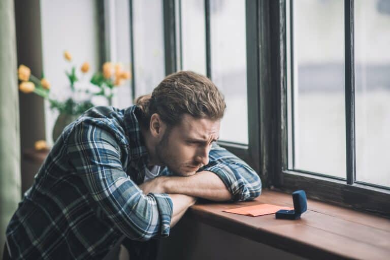 young man looking at ring box deciding on making a marriage proposal