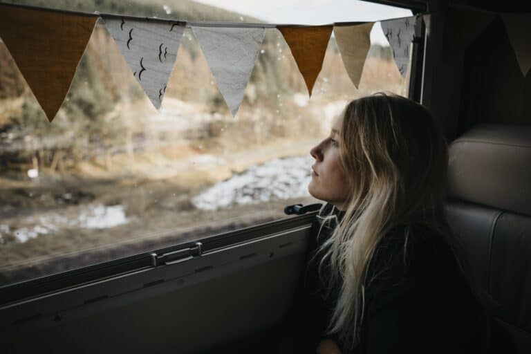 Pensive young woman all alone looking out of bus window