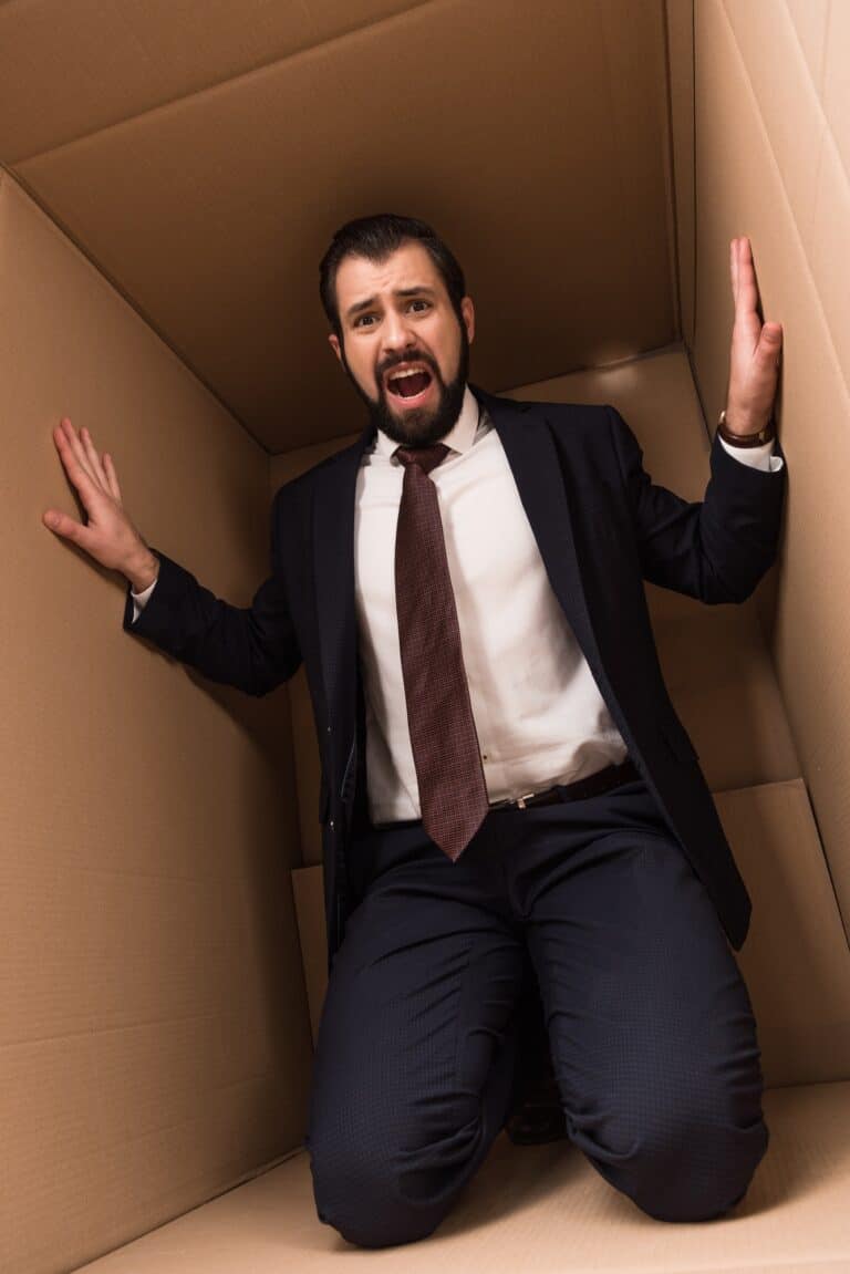 stressed businessman caught in a box that holds him back